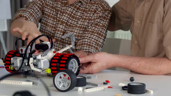 Senior Man Helps His Grandson To Assemble Toy Vehicle