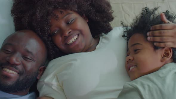 Happy African American Family Cuddling on Bed