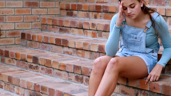 Sad schoolgirl sitting alone on staircase