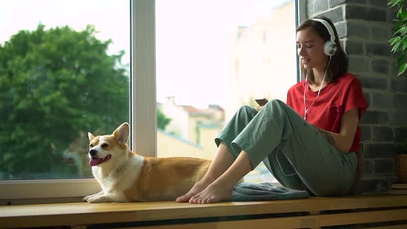 Woman with Corgi Dog Listen to Music in Headphones Moving Head and Enjoying Avki