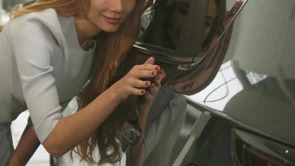 Cropped Close Up of a Woman Checking Out Car Paint on a New Automobile at the Dealership