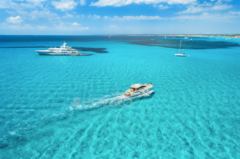 erial view of floating boat with people in transparent sea at sunny day in summer. Top view from drone. Seascape with luxury yachts in motion in bay
