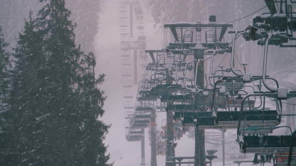 Ski Lift on Ski Resort, Slow Motion. Skiers Climb Up on Ski Chair Elevator To Ski Slope with Falling