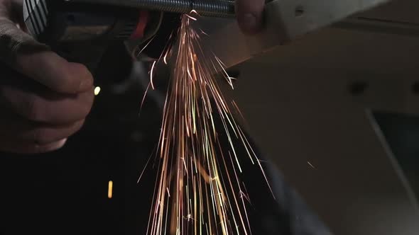 worker at the factory cuts a metal rod. Sparks fly in different directions.