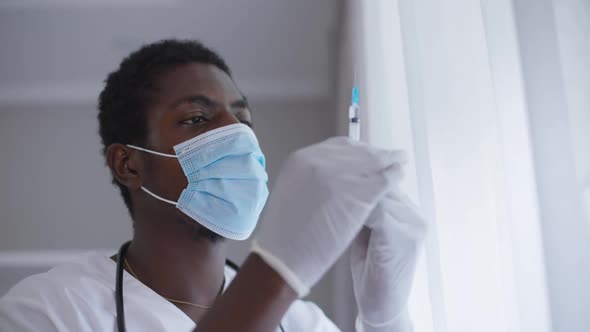 Closeup Expert African American Doctor on Coronavirus Face Mask Holding Syringe with Covid19 Vaccine