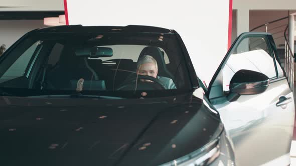 Cheerful Young Woman Showing Her New Car Key at Dealership