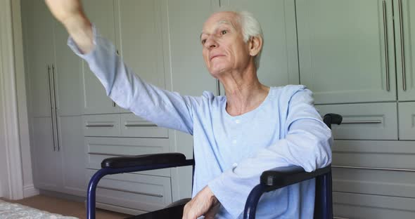 Senior man in wheelchair waving at home