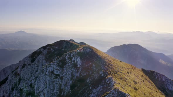 Epic View of a Man Standing on top of the Mountain Close to the Tent on a Beautiful Summer day 