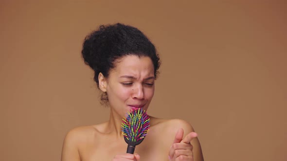 Beauty Portrait of Young African American Woman Dancing and Singing Merrily in Hairbrush