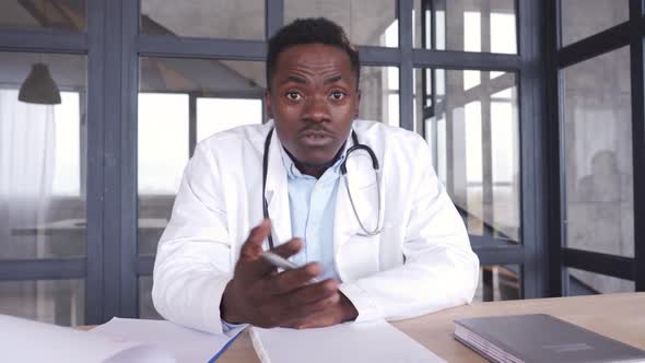 Black Male Doctor Talking To Web Cam During Virtual Telemedicine Advice