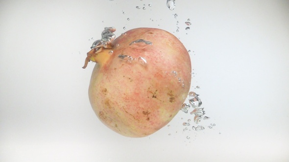 Pomegranate falls into the water in slow motion.