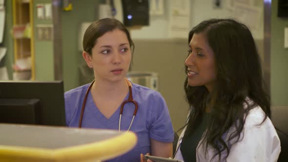 Female doctor and nurse work on a computer together in a hospital.