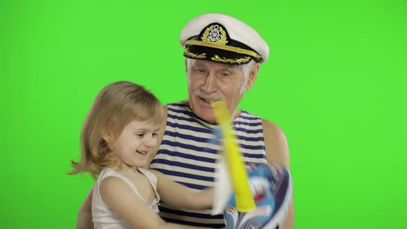 Elderly Sailor Man Grandfather Plays with Granddaughter. Happy Little Child