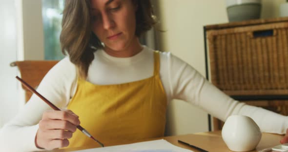 Caucasian woman with brown hair painting at home