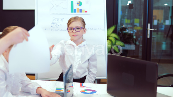 Business Children Sitting at a Table, While a Beautiful Girl Colleague Giving a Presentation