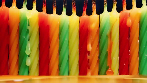 Closeup Row of Colorful Birthday Candles Burning in Timelapse on Black Background