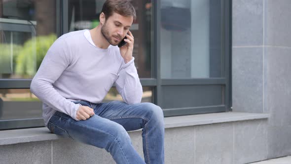 Handsome Man Talking on Phone while Sitting Outside Office