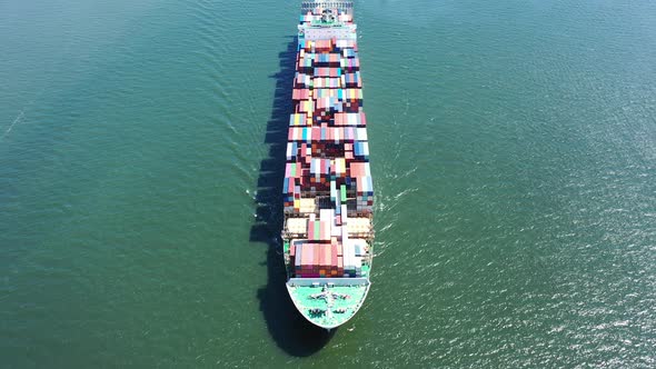 An aerial shot of a cargo ship with colorful containers on-board. The drone dolly in while tilted do