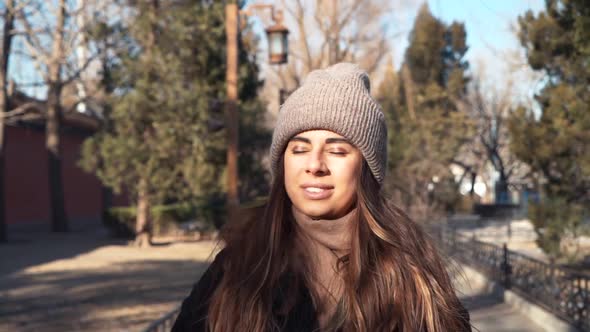 Tourist Woman Walking on Green Summer Park. Carefree Woman Going on Flowering Garden in Hat. Winter