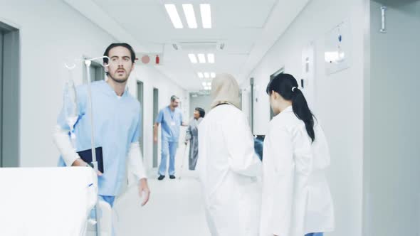 Doctors in hospital corridor pass heathcare worker helping elderly patient 4k