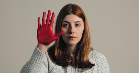 Sad Girl Raises Her Hand Painted Red to Stop and Protest Against Violence