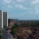 Drone moving towards Buildings in India with dry land and greenery on the other side - VideoHive Item for Sale