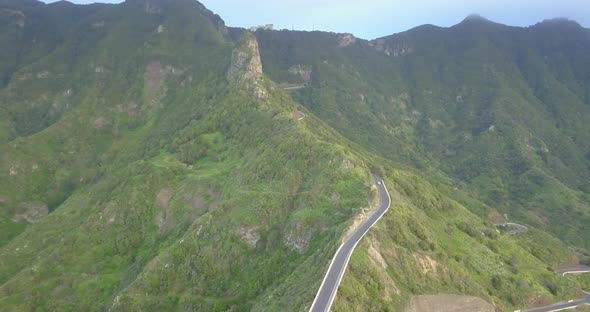 Aerial drone view of green mountains and road in Tenerife, Spain.