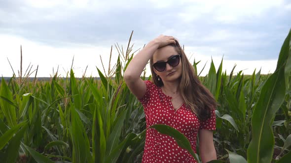 Beautiful Cute Girl in Sunglasses Looking Into Camera and Straightening Her Long Brown Hair Against