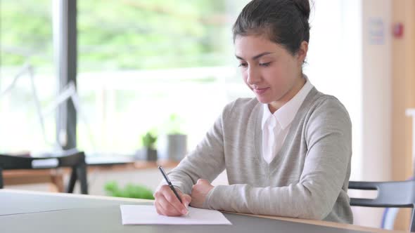 Serious Indian Woman Writing on Paper at Work 