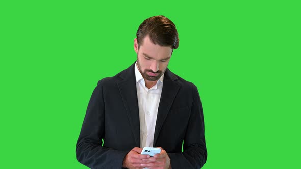 Handsome Happy Business Man Texting on Smartphone on a Green Screen Chroma Key