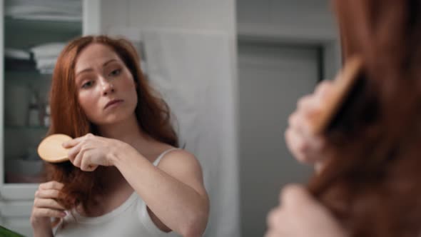 Redhead woman brushing hair in the bathroom. Shot with RED helium camera in 4K.