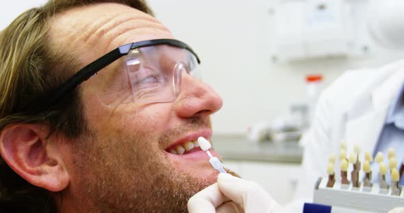 Female dentist showing teeth shades to male patient