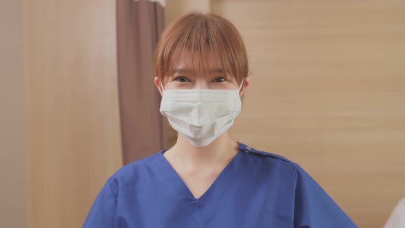 Portrait of Asian nurse put protective surgical mask on to prevent covid virus pandemic in hospital.