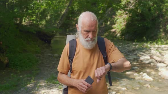 Old Man Uses Bracelet and Mobile Phone While Traveling in the Forest