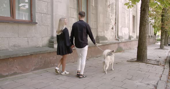 Man and Woman Walking with Their Pet at the City