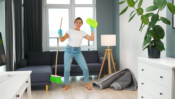 Woman Cleaning the House and Having Fun Dancing with a Broom and Washcloth