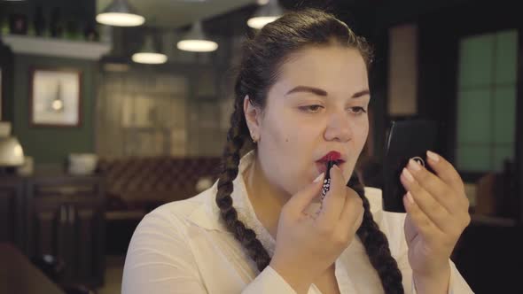 Portrait of Attractive Confident Plump Woman Painting Lips with Bright Red Lipstick