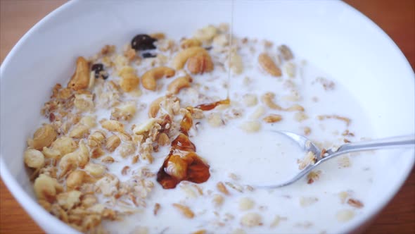 Slow Motion Milk Pouring in Bowl of Muesli Breakfast Cereals. Healthy Food