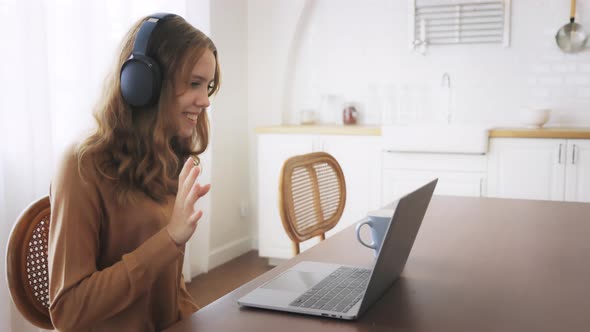 Girl Using Laptop with Headphones and Waving Hand