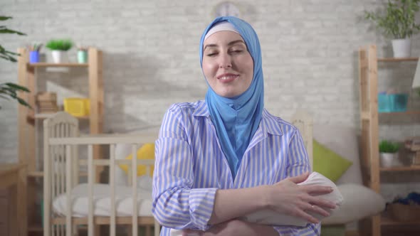 Happy Young Mother in a Headscarf Holding a Newborn Baby