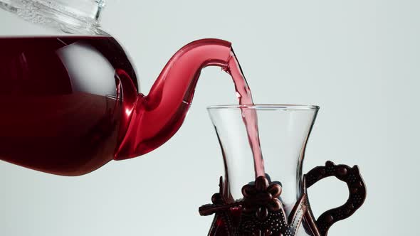 Pouring Red Fruit Tea in Armudu Glass on White Background