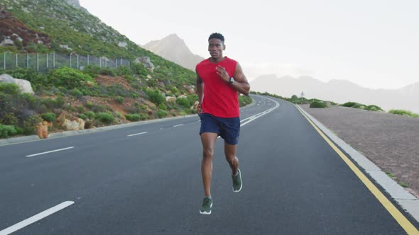 African american man exercising outdoors running on a coastal road