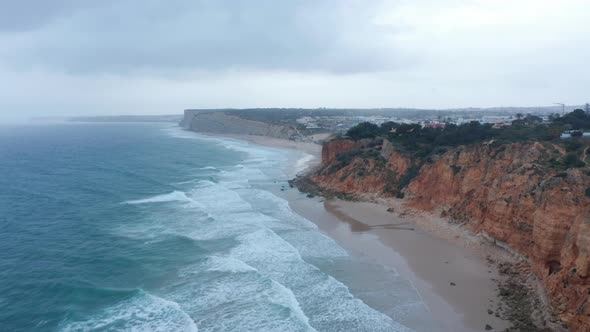 Amazing Aerial Drone View of Sandy Lagos Beach with Waves Crashing Against Shore Cloudy Day Dolly in