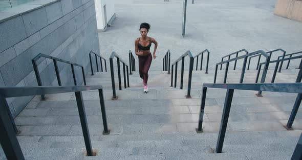 Sportive Black Woman Runs Up Stairs with Railings on Street