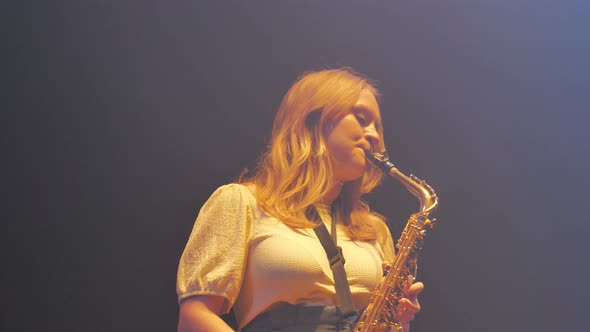 Close Up of Female Saxophonist Playing Music on Instrument on Stage Full of Haze