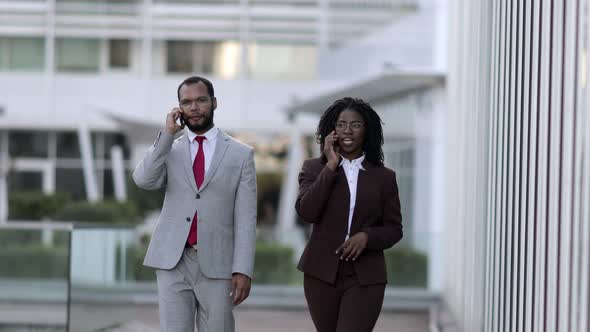 Two Confident Managers Walking on Street with Smartphones.