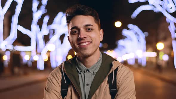 Portrait of Handsome Happy Guy 20s Laughing in Slow Motion While Standing in Downtown During Night