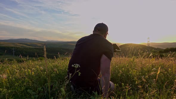 Man with laptop sitting and networking in the country