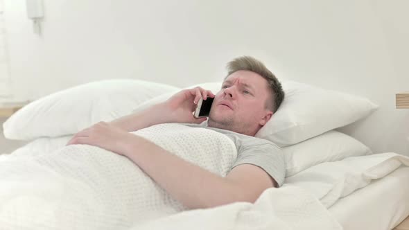Man Getting Angry While Talking on The Phone in Bed