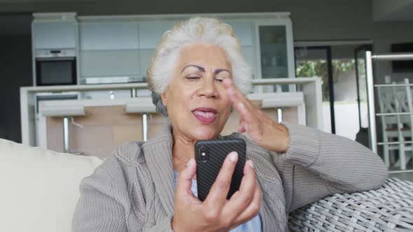 African american senior woman blowing kisses having a video call on smartphone at home